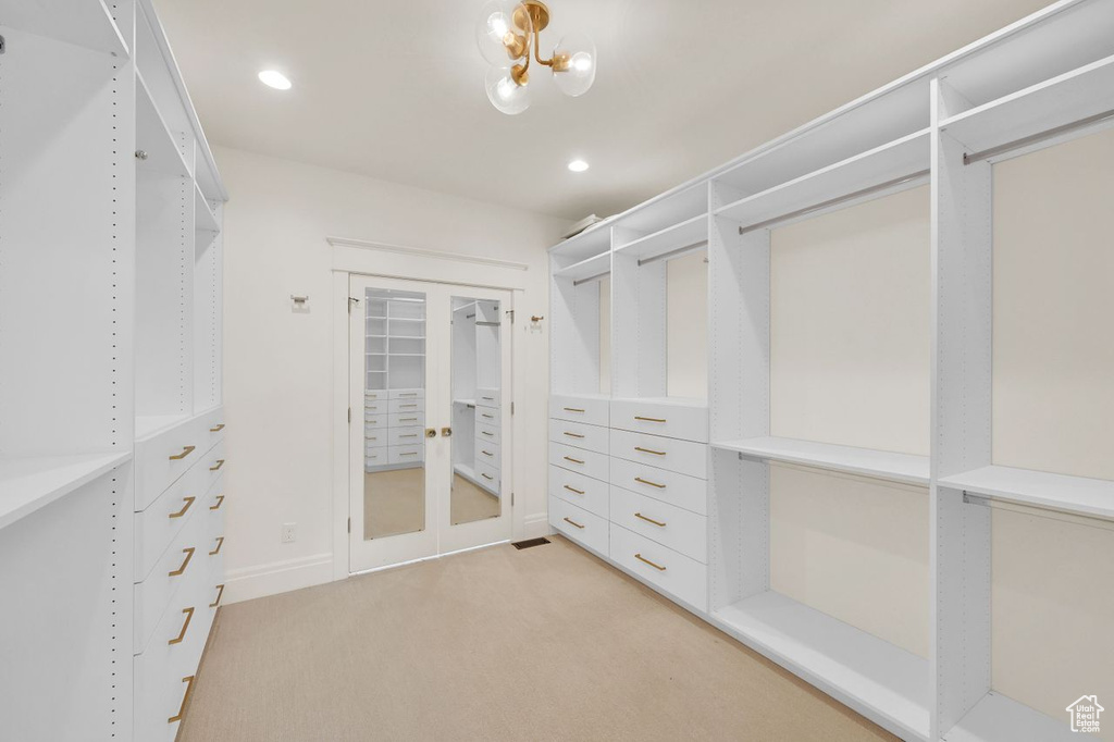 Walk in closet with light carpet and french doors