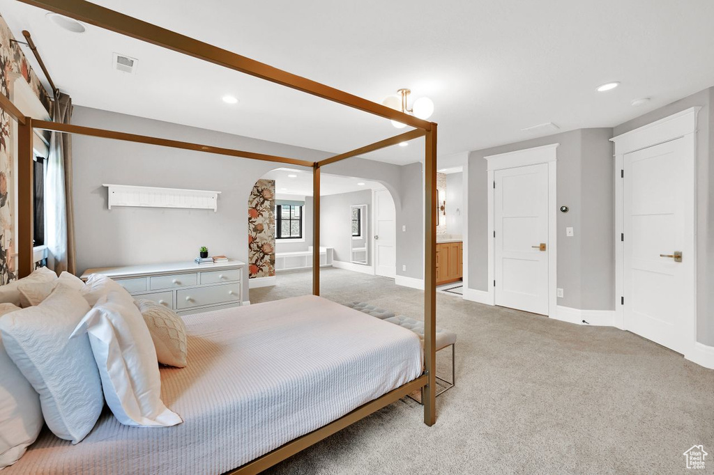 Bedroom featuring light colored carpet, arched walkways, recessed lighting, baseboards, and visible vents