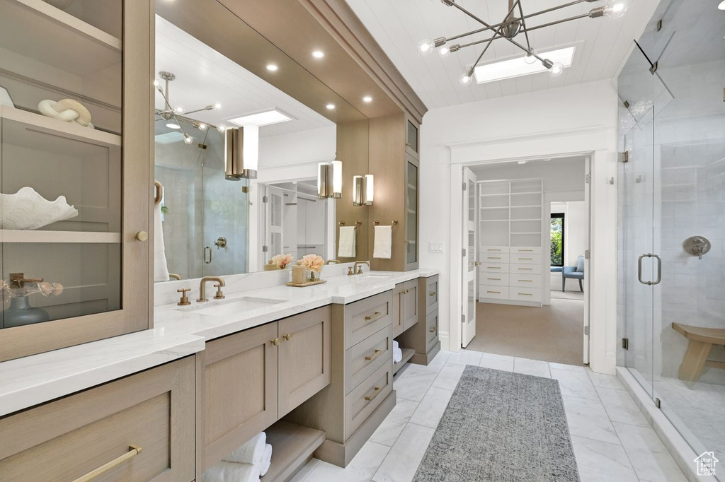 Full bath featuring double vanity, a chandelier, a sink, and a stall shower