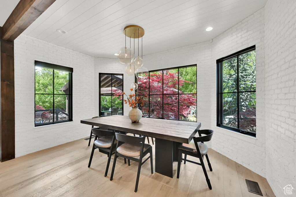 Dining room with visible vents, light wood-style floors, and brick wall