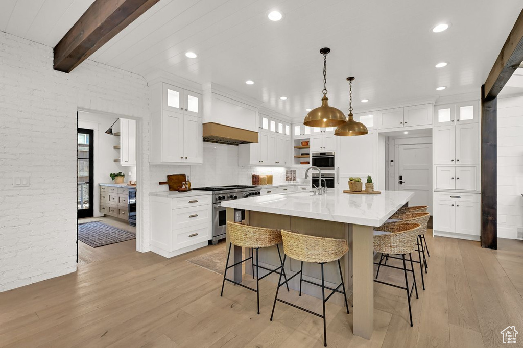 Kitchen featuring appliances with stainless steel finishes, a kitchen bar, and light wood-type flooring