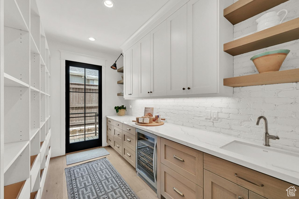 Bar featuring tasteful backsplash, a sink, beverage cooler, indoor bar, and recessed lighting