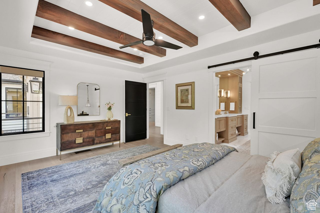 Bedroom featuring a barn door, wood finished floors, baseboards, beamed ceiling, and recessed lighting