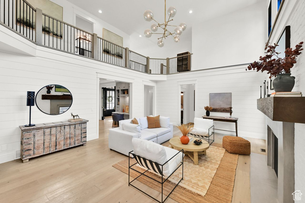 Living area featuring a towering ceiling, wood finished floors, a fireplace, recessed lighting, and a chandelier