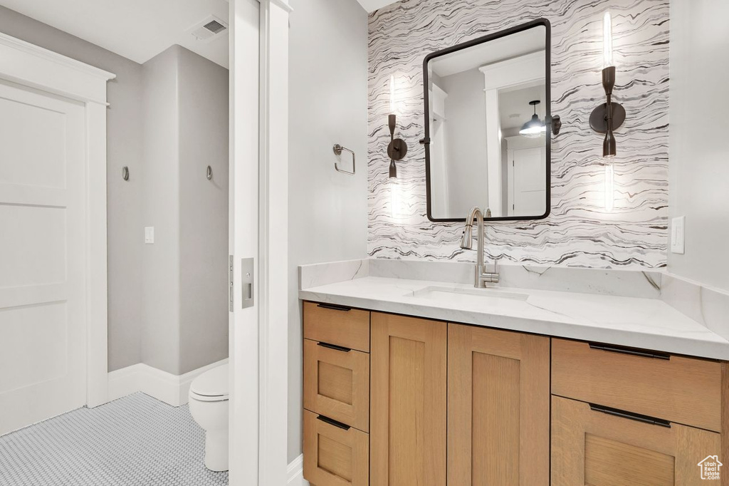 Bathroom featuring visible vents, tile patterned flooring, vanity, toilet, and wallpapered walls