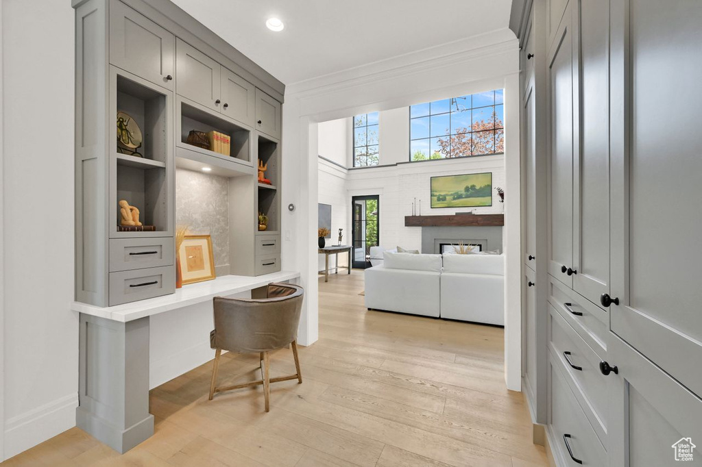 Hall with light wood finished floors, built in shelves, recessed lighting, baseboards, and ornamental molding