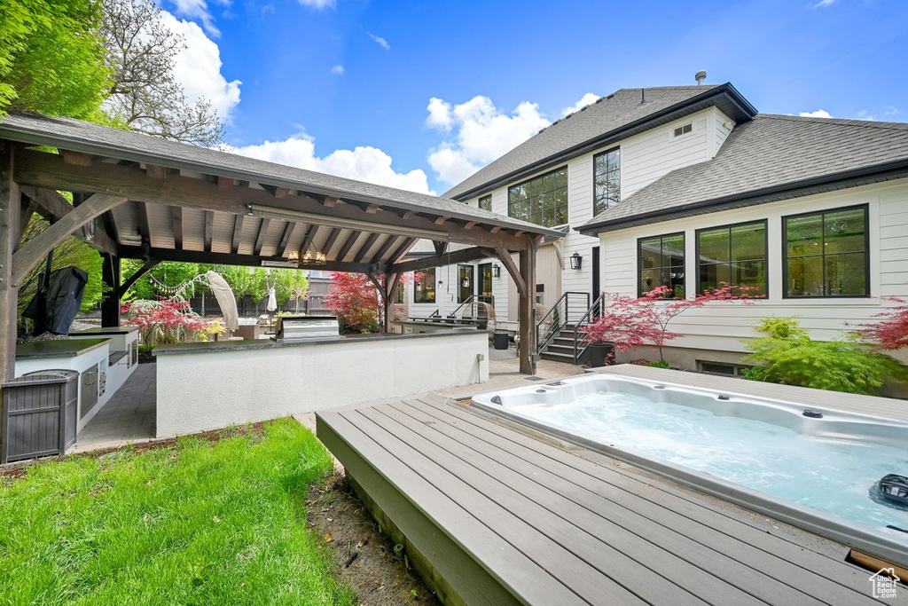Wooden terrace featuring hot tub deck surround and a gazebo