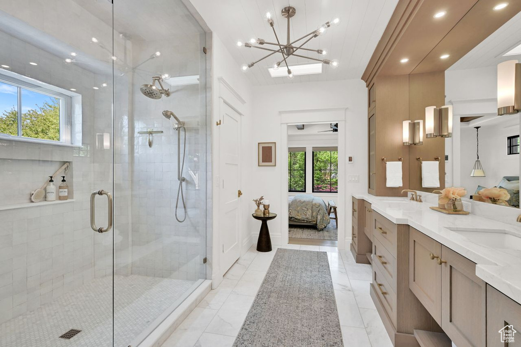 Ensuite bathroom featuring a sink, an inviting chandelier, a shower stall, and ensuite bath
