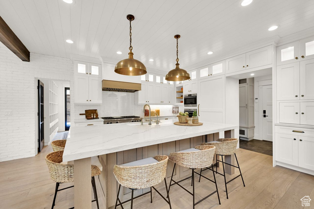 Kitchen with a sink, light wood-style floors, and white cabinetry