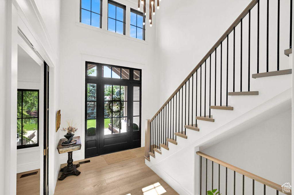 Foyer featuring a healthy amount of sunlight, stairway, wood finished floors, and a towering ceiling