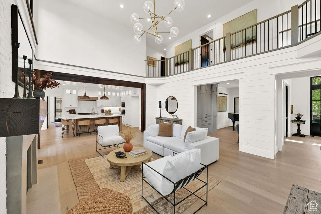 Living area featuring light wood-style floors, a high ceiling, recessed lighting, and a notable chandelier