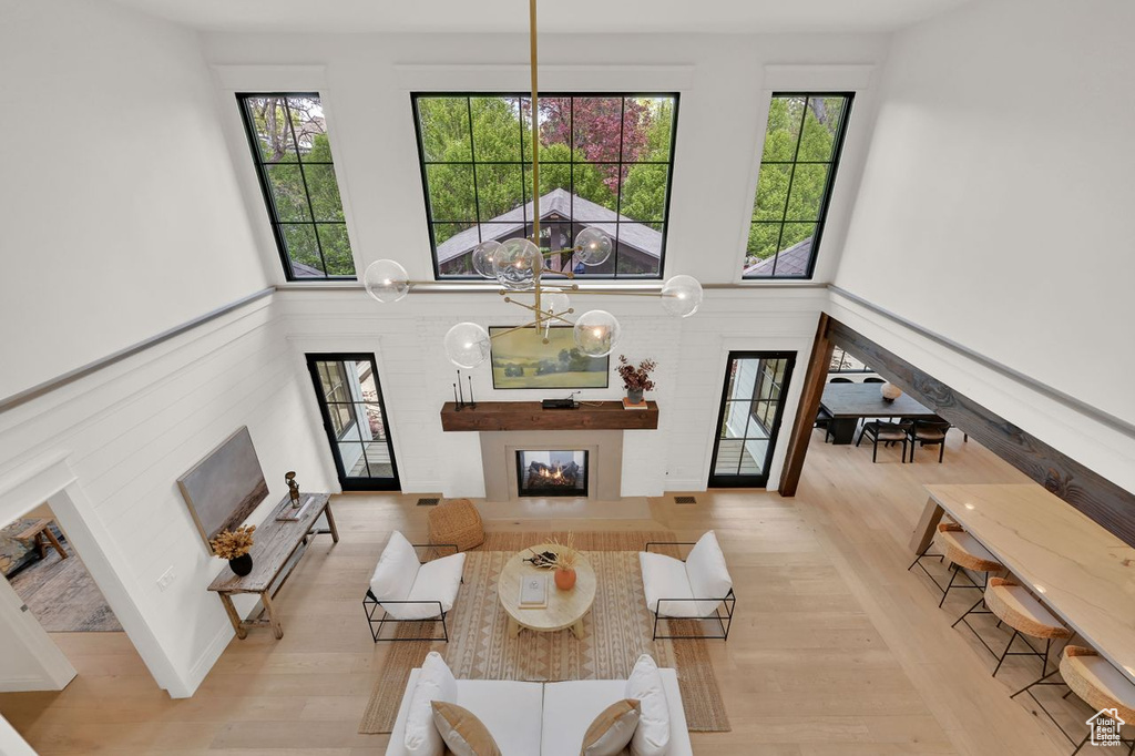 Living room with a towering ceiling, a glass covered fireplace, and wood finished floors