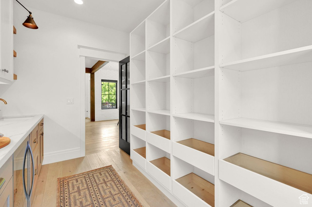 Hallway with recessed lighting, baseboards, a sink, and light wood-style floors