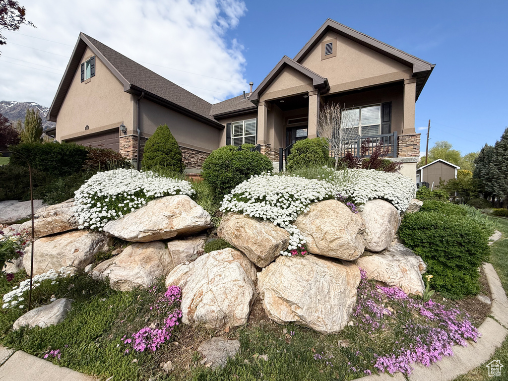 View of front of property with a garage, stucco siding, and stone siding
