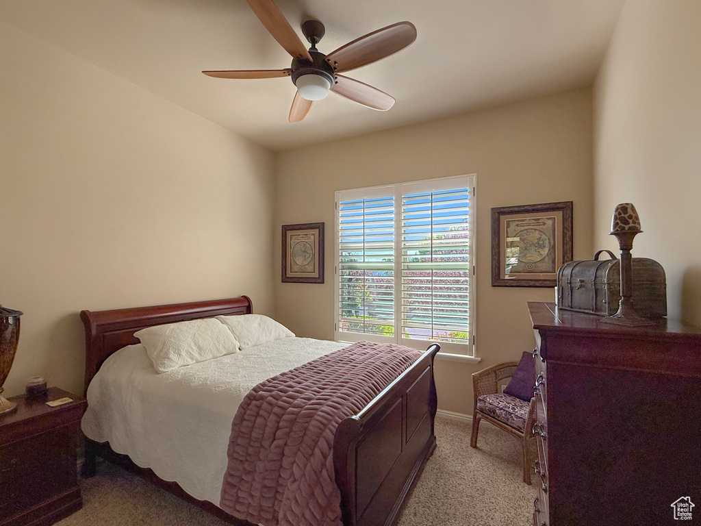 Bedroom with light colored carpet, baseboards, and ceiling fan