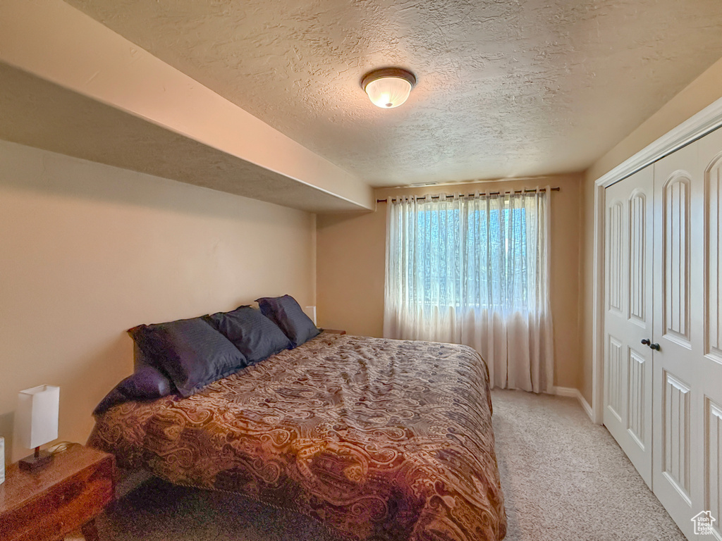 Bedroom with carpet, a closet, and a textured ceiling