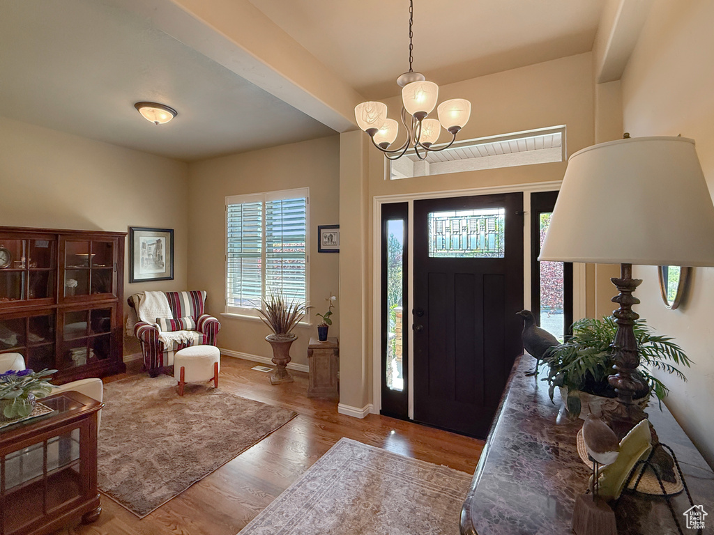 Entrance foyer with an inviting chandelier, baseboards, and wood finished floors