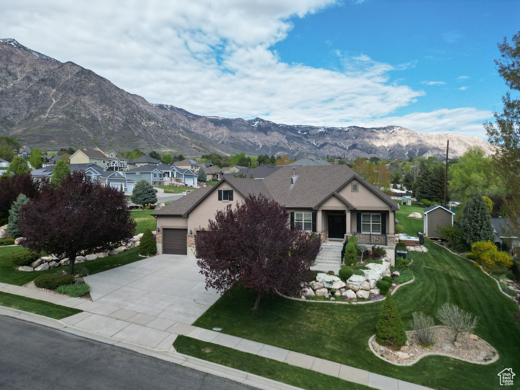 Single story home with a garage, a front lawn, stucco siding, a mountain view, and driveway