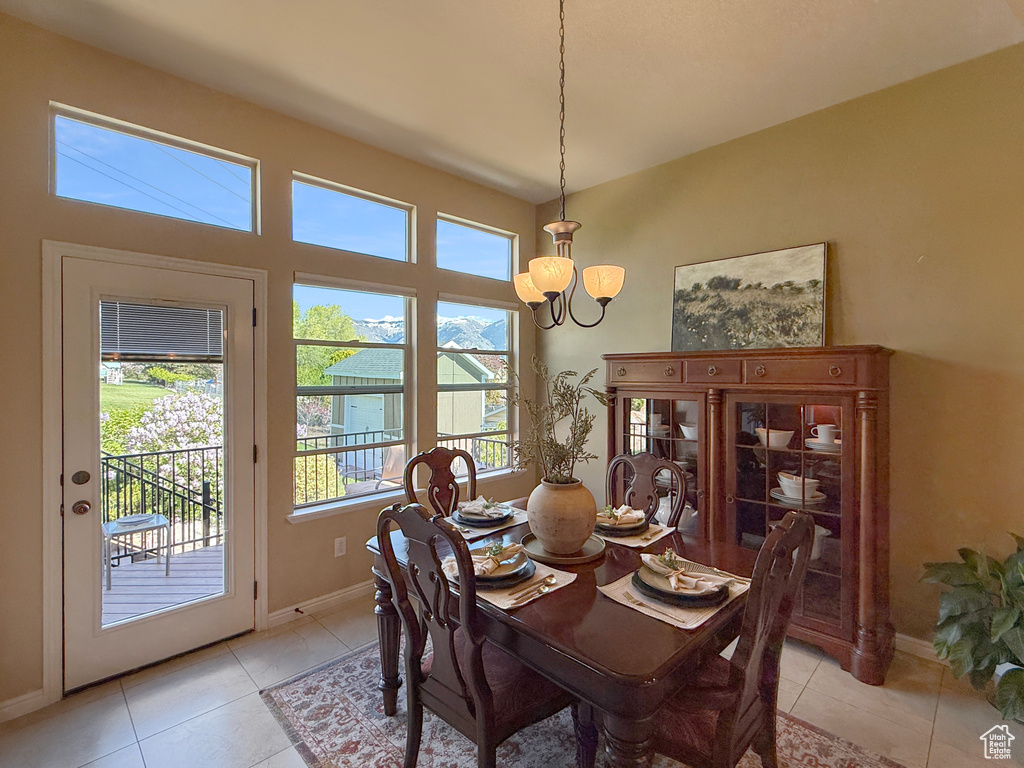 Dining space with light tile patterned floors, baseboards, and a notable chandelier