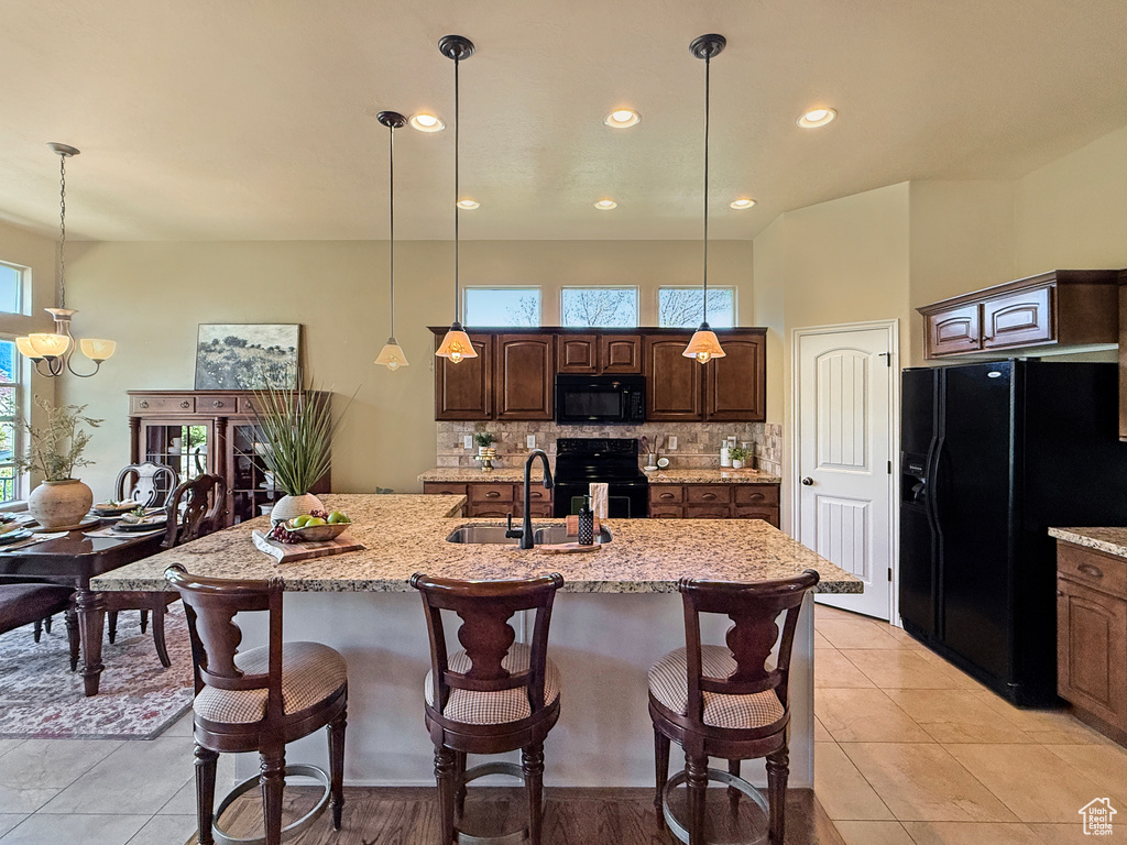 Kitchen featuring a sink, black appliances, a breakfast bar, and tasteful backsplash