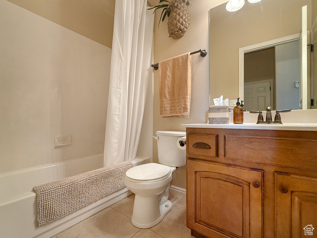 Full bathroom featuring vanity, toilet, baseboards, tile patterned floors, and shower / bath combo