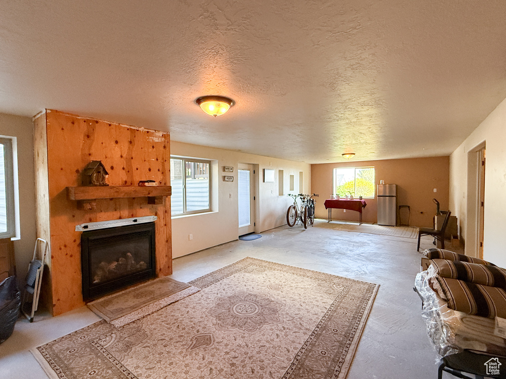 Living room featuring plenty of natural light, a textured ceiling, and a glass covered fireplace