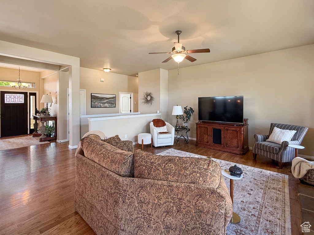 Living area with baseboards, ceiling fan with notable chandelier, and wood finished floors