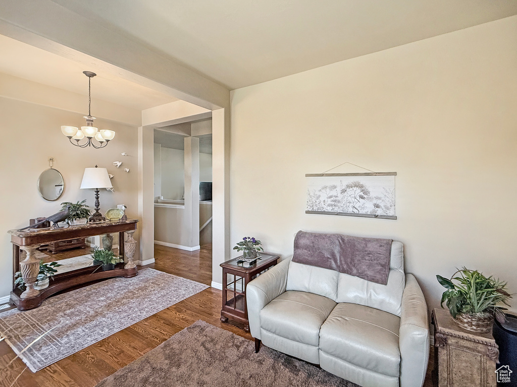 Living area with baseboards, a notable chandelier, and wood finished floors