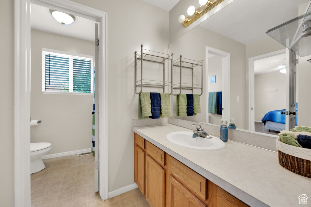 Full bathroom with vanity, baseboards, ensuite bathroom, and toilet