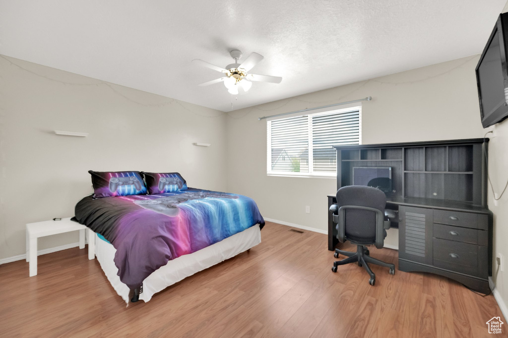 Bedroom featuring light wood-style floors, baseboards, and ceiling fan