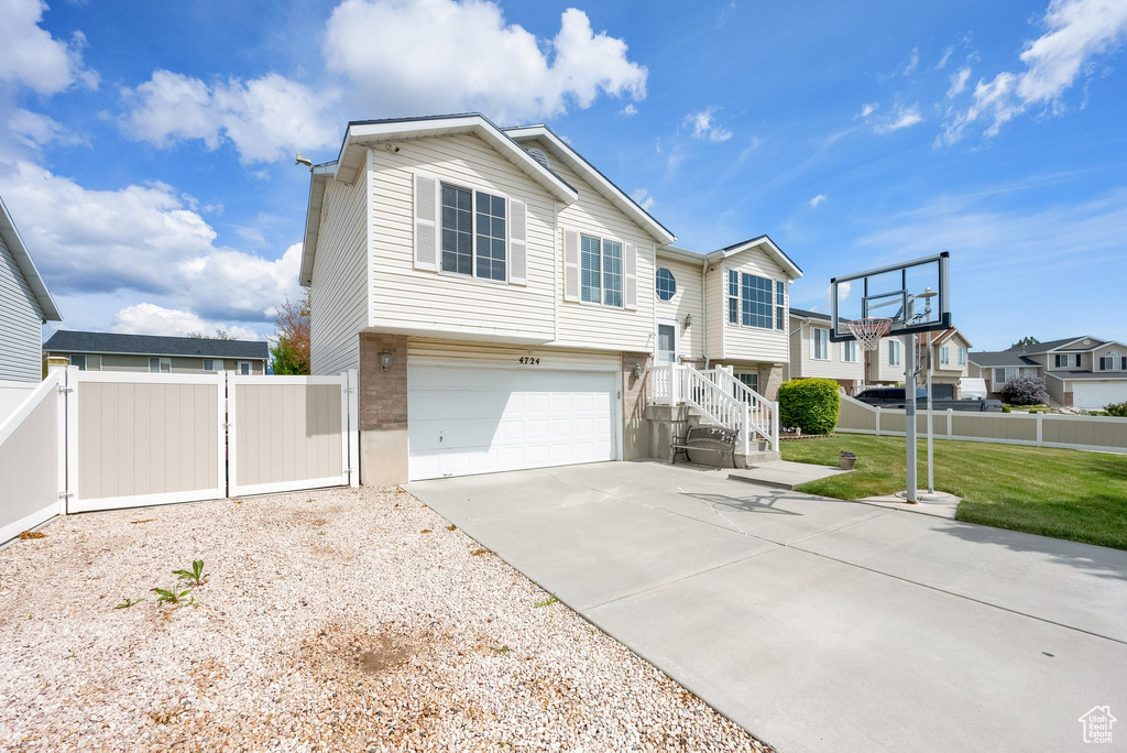 View of front of home featuring fence, driveway, a residential view, and a garage