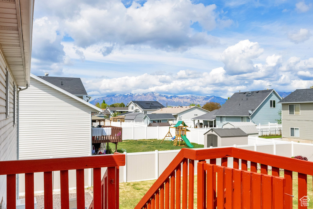View of yard featuring a residential view, an outdoor structure, a fenced backyard, a storage unit, and a deck with mountain view