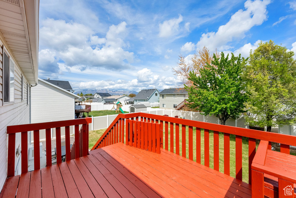 Deck featuring a lawn, a fenced backyard, a playground, and a residential view