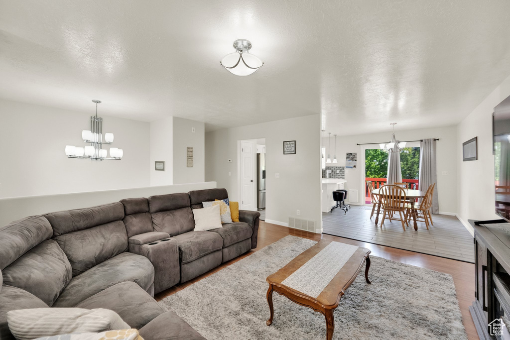 Living area with baseboards, a chandelier, wood finished floors, and visible vents