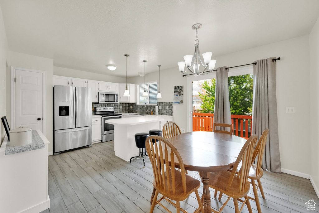 Dining space featuring light wood-type flooring, baseboards, and a chandelier