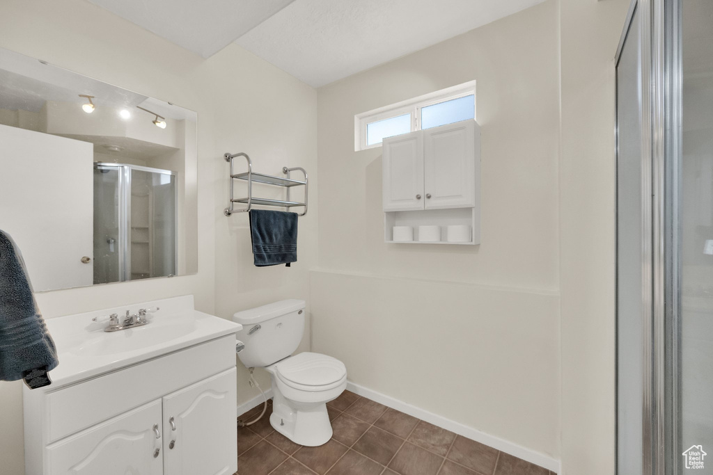 Full bath with vanity, toilet, tile patterned floors, baseboards, and a shower stall