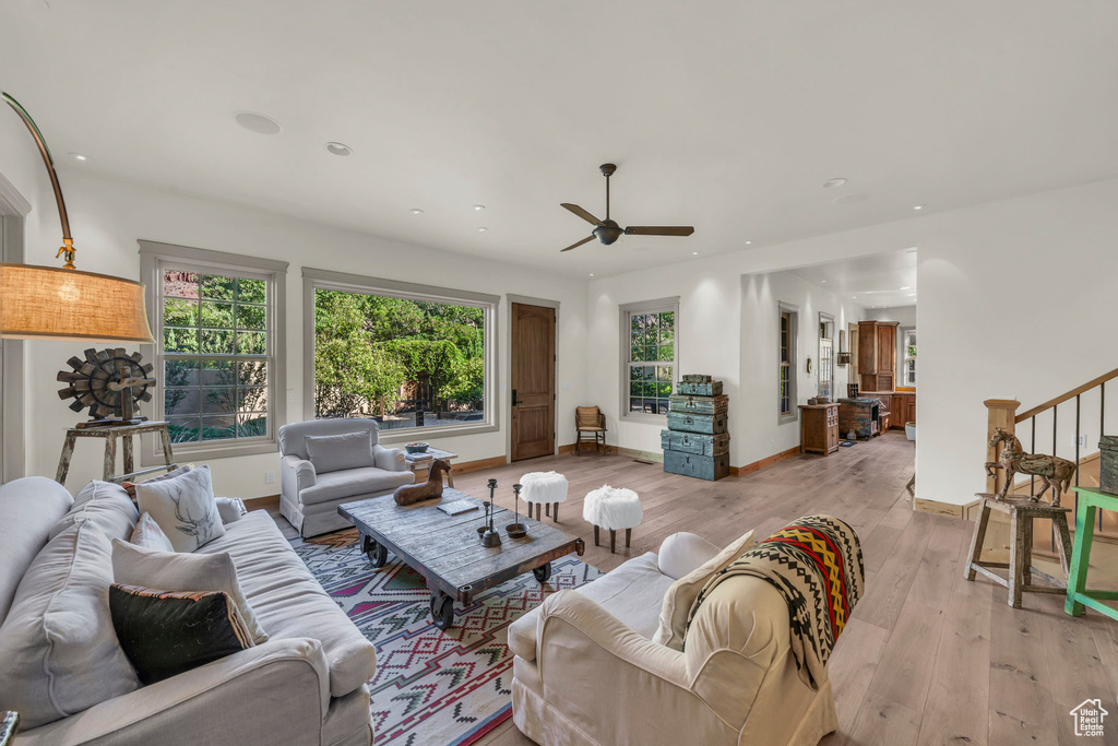 Living area featuring light wood-style flooring, a ceiling fan, baseboards, recessed lighting, and stairway