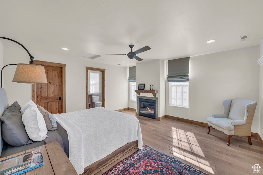 Bedroom with recessed lighting, visible vents, a glass covered fireplace, and light wood finished floors