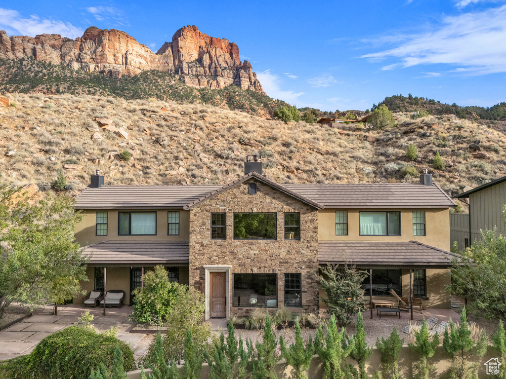 Exterior space with a patio, a mountain view, stucco siding, and a chimney