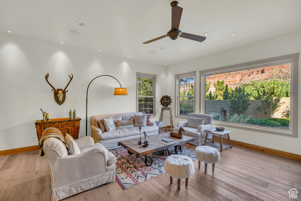 Living room featuring a ceiling fan, baseboards, and light wood-style flooring