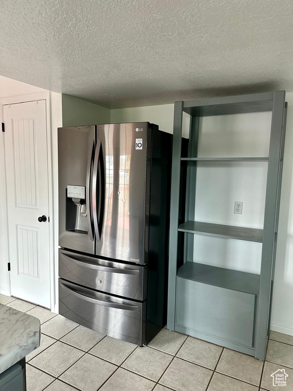 Kitchen featuring stainless steel fridge, a textured ceiling, and light tile patterned floors