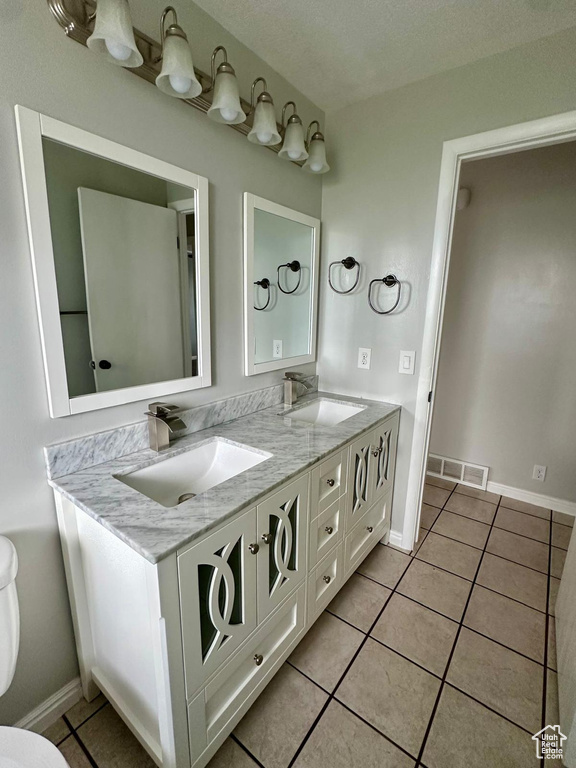 Full bath with a sink, tile patterned floors, double vanity, and visible vents