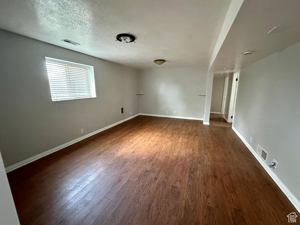 Unfurnished room with visible vents, baseboards, and dark wood-style floors