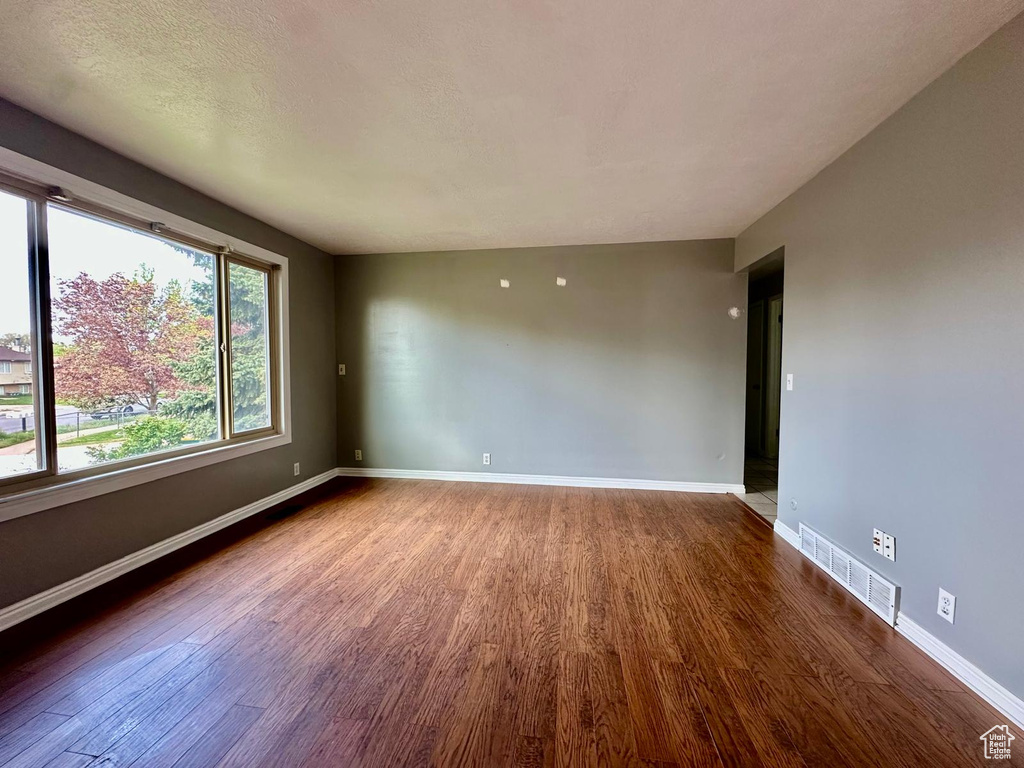Empty room with baseboards, visible vents, and wood finished floors