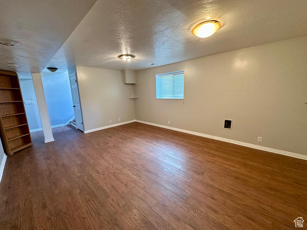 Basement featuring baseboards, built in features, a textured ceiling, and dark wood-style floors
