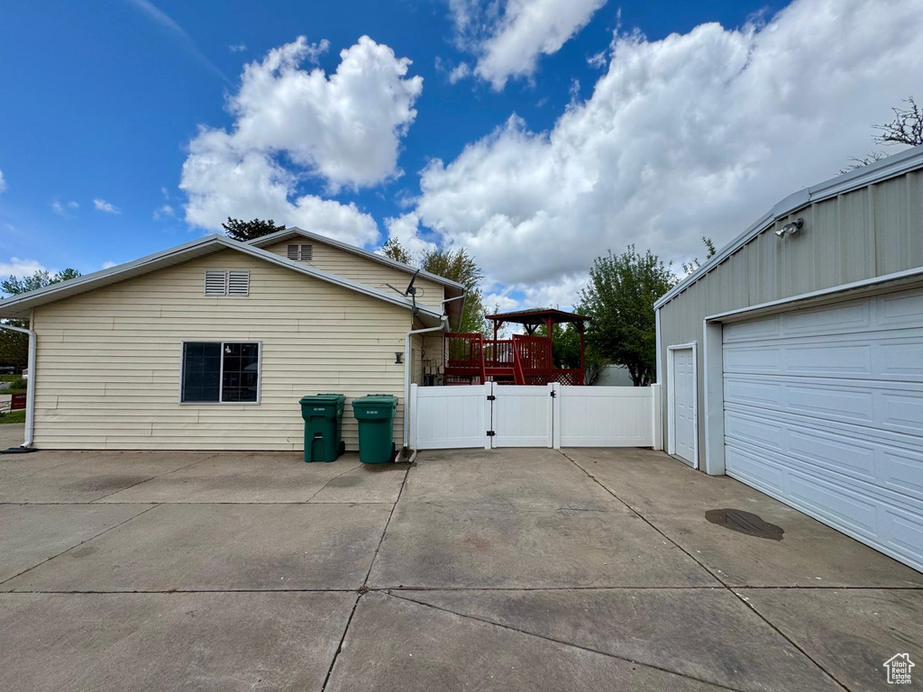 View of side of property with a garage, a gate, driveway, and fence