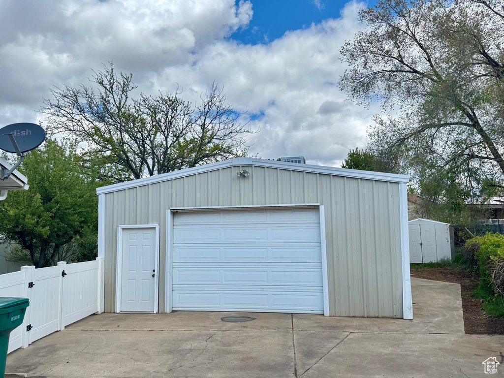 Detached garage featuring fence and concrete driveway