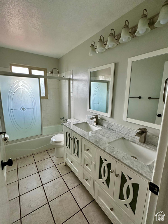 Bathroom with double vanity, a sink, combined bath / shower with glass door, and tile patterned floors