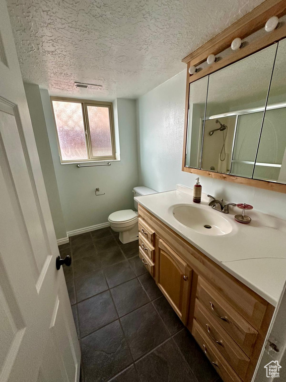 Full bathroom featuring vanity, a shower stall, a textured ceiling, and visible vents
