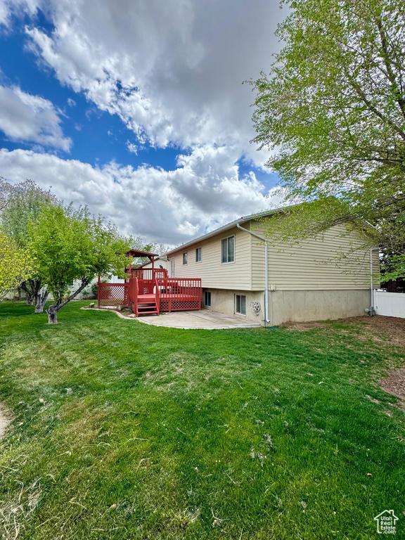 Back of property with a yard, a patio area, and a deck
